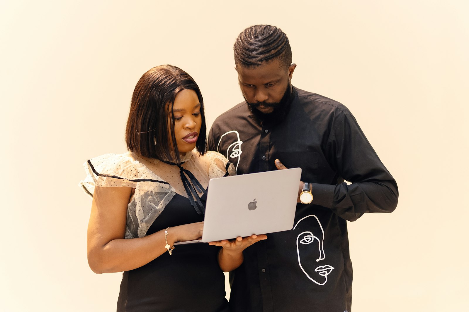 Two parents standing together, both looking closely at a laptop